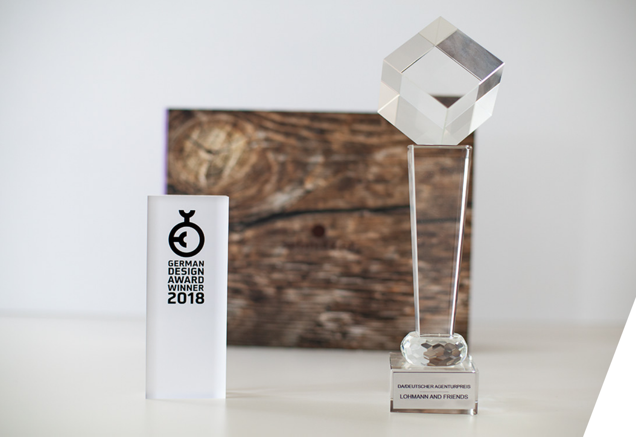 Holzbroschüre des sebnitzer fensterbau, vor der ein Pokal des Deutschen Agenturpreises und des German Brand Award 2018 stehen